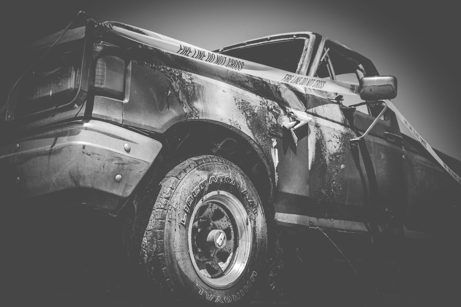 Black and white photo of a damaged truck behind police tape.