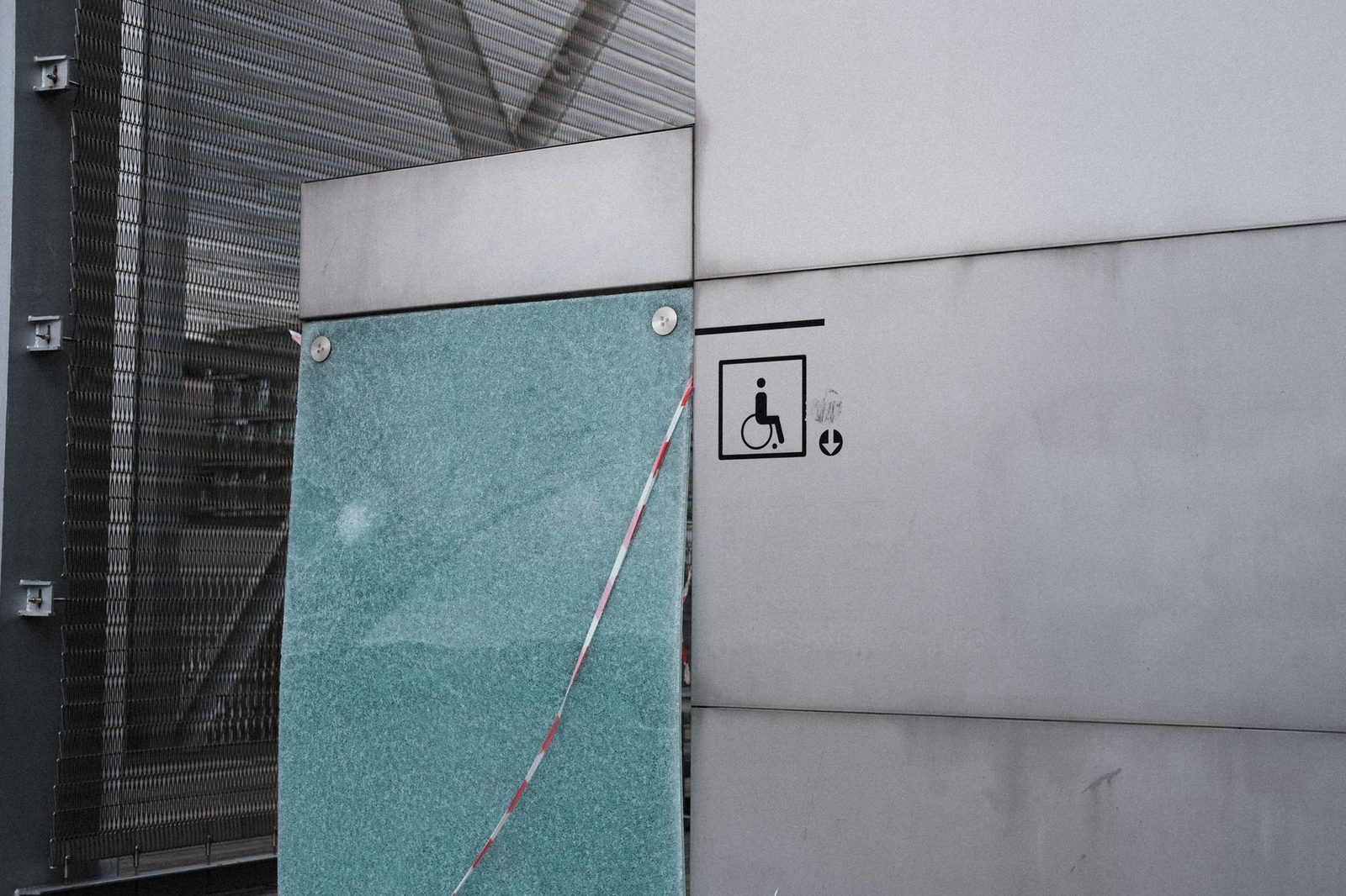 Fachada de un edificio con el símbolo internacional de accesibilidad para sillas de ruedas junto a la entrada.