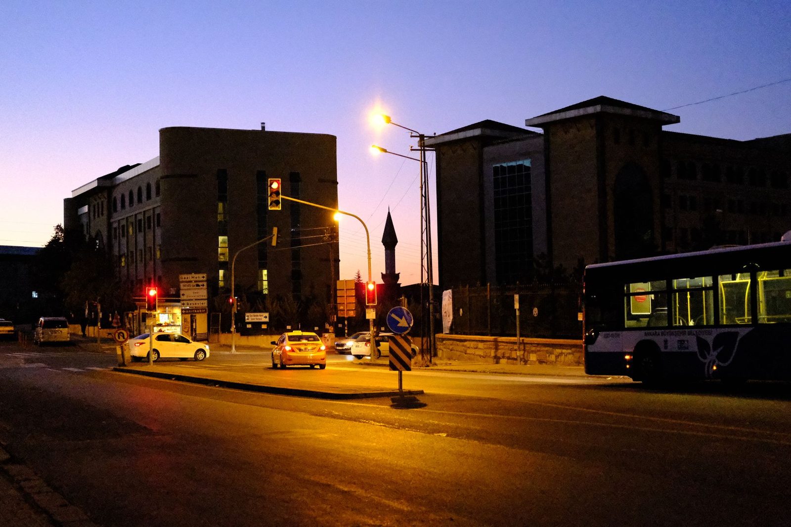 Busy evening intersection in Ankara, Türkiye, with traffic lights and vehicles at twilight.