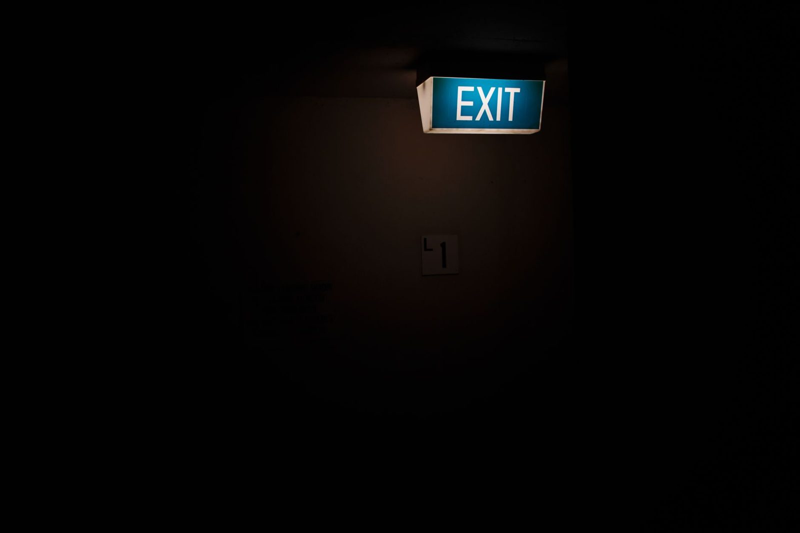 Dimly lit interior with a bright illuminated exit sign overhead.