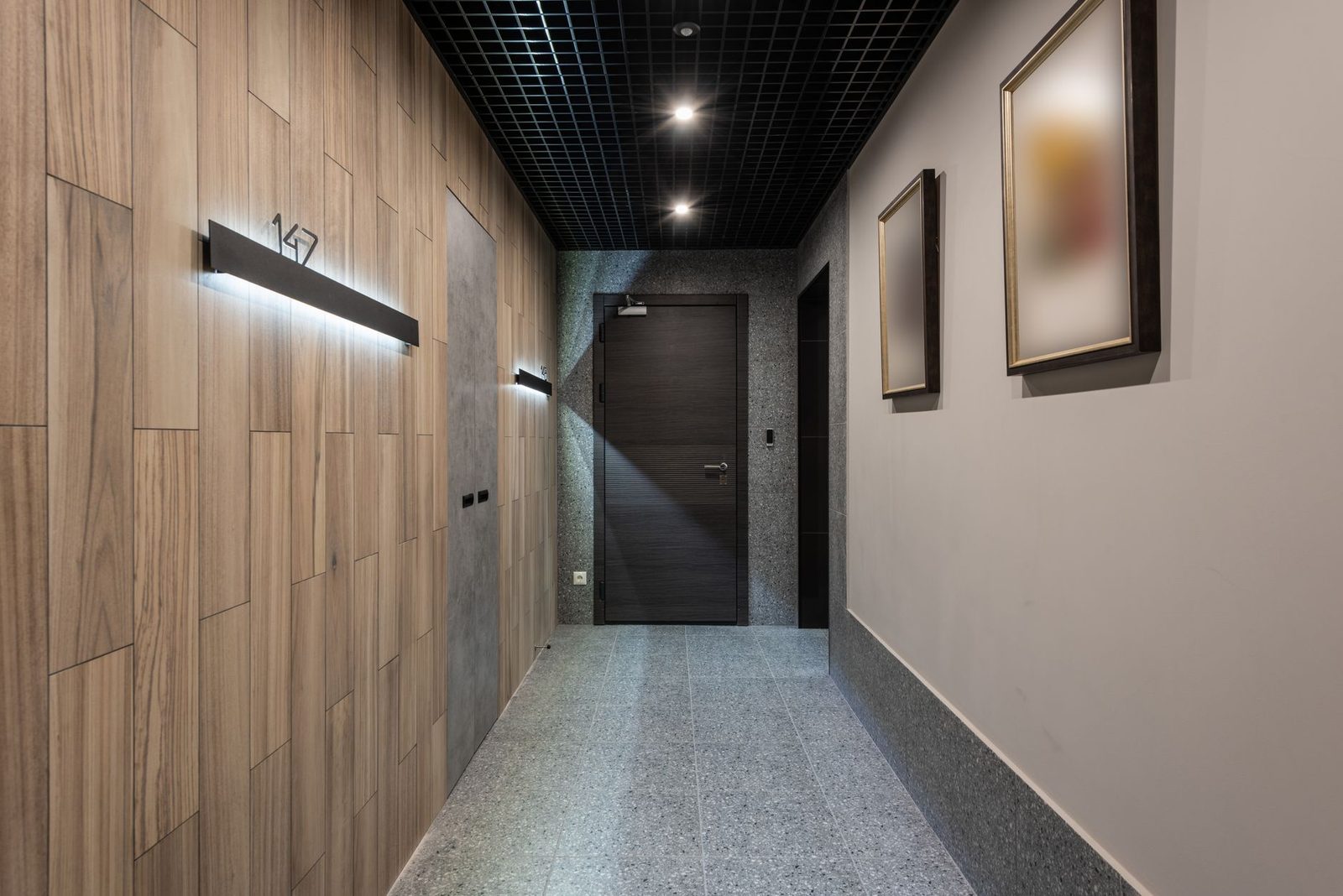Hallway with illuminated room numbers beside doors in a hotel corridor.