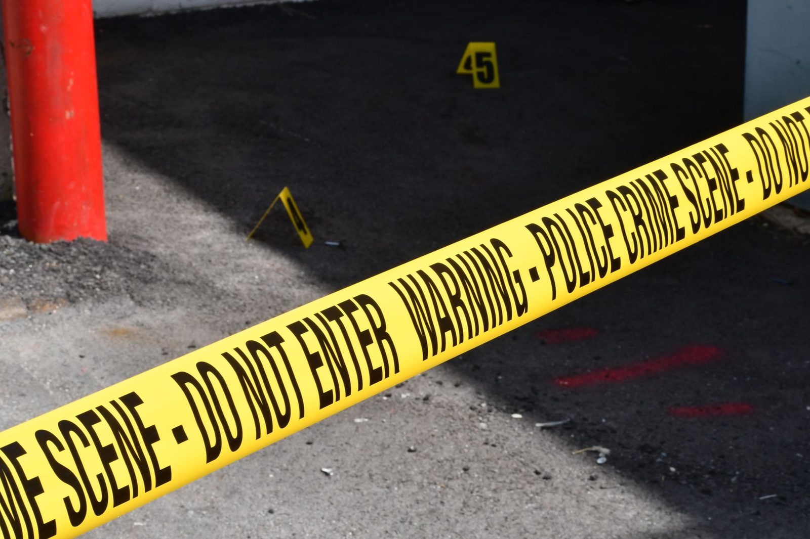 Yellow police tape stretched across a concrete street marks off a restricted area.